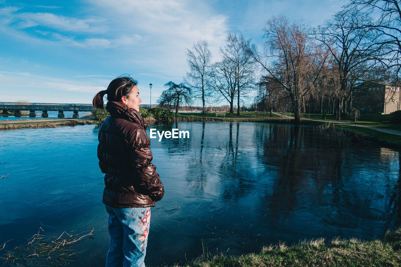 Woman standing by lake against sky