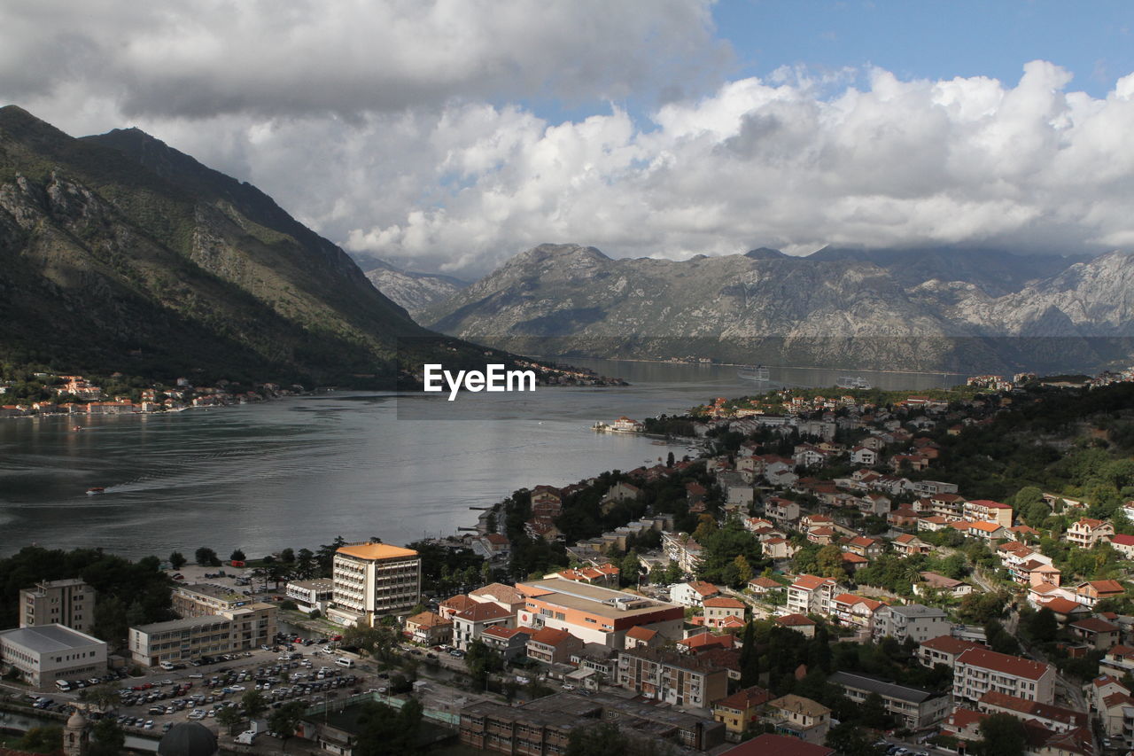 Town by lake and mountains against sky