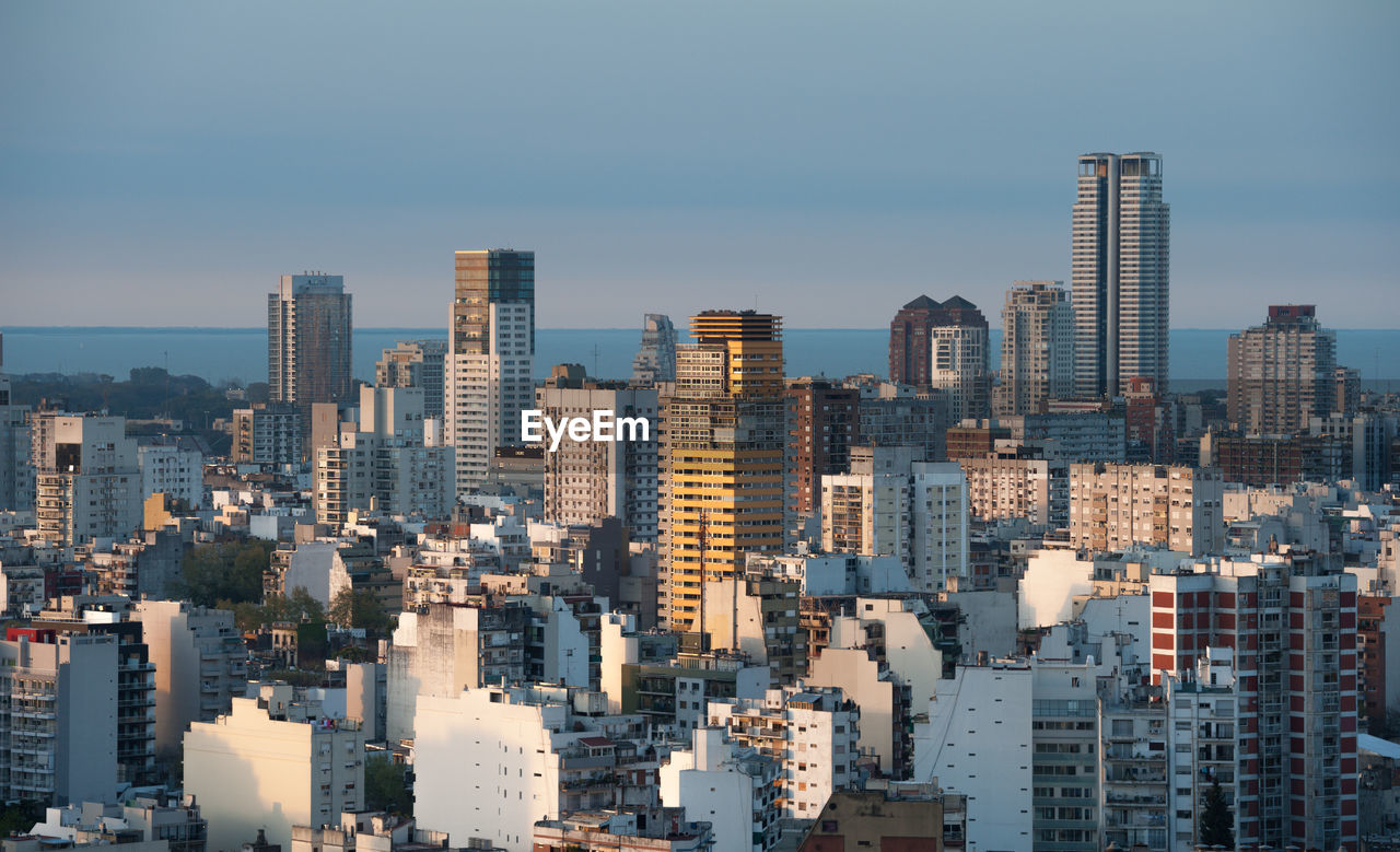 AERIAL VIEW OF BUILDINGS IN CITY AGAINST SKY DURING SUNSET