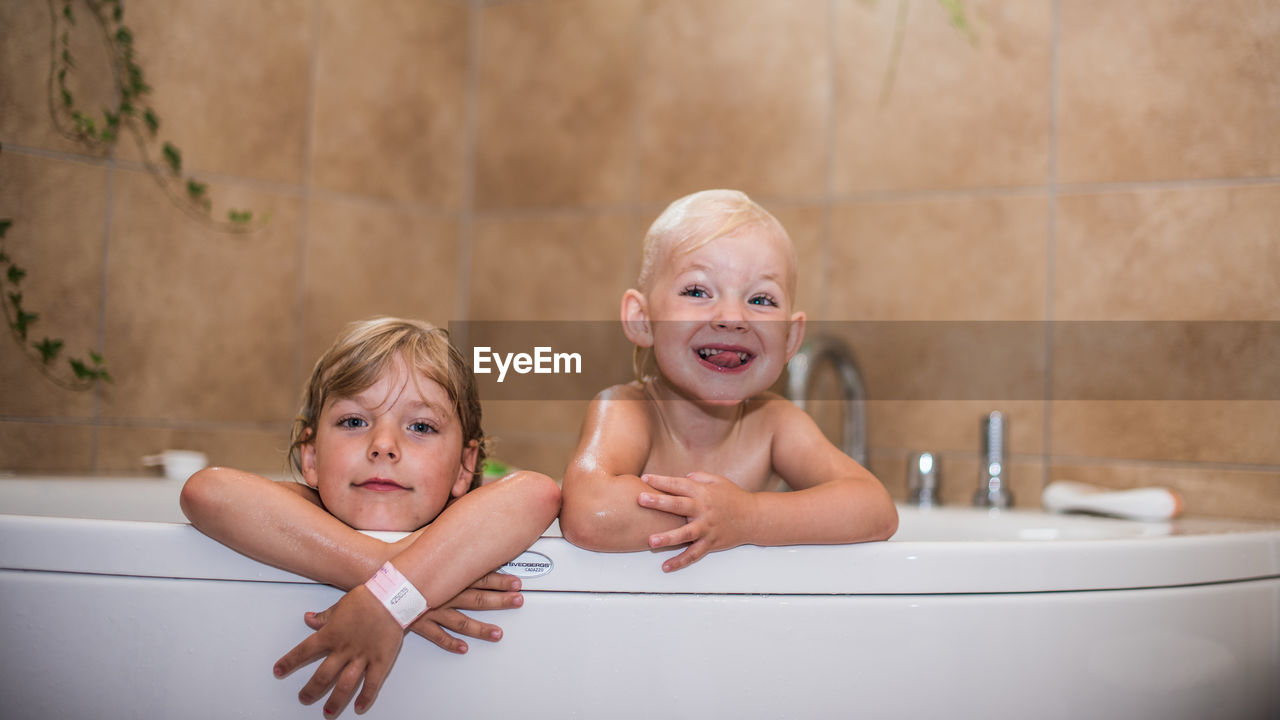 Happy sisters in bathtub at home