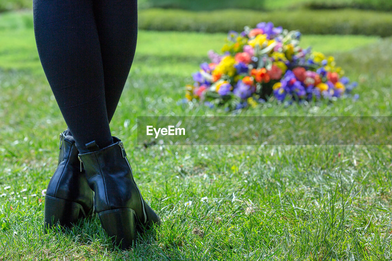 LOW SECTION OF WOMAN STANDING ON GRASS