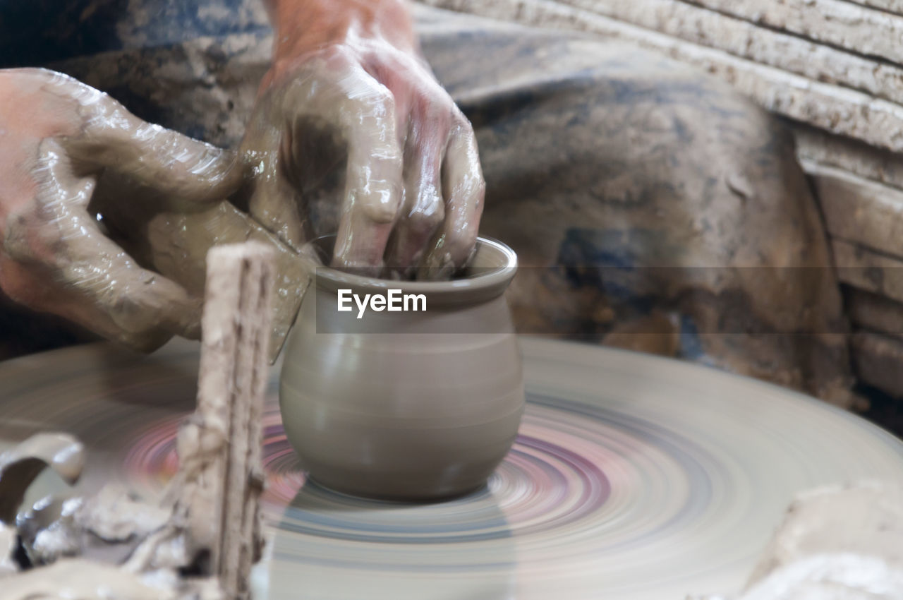 Midsection of potter making pot at workshop