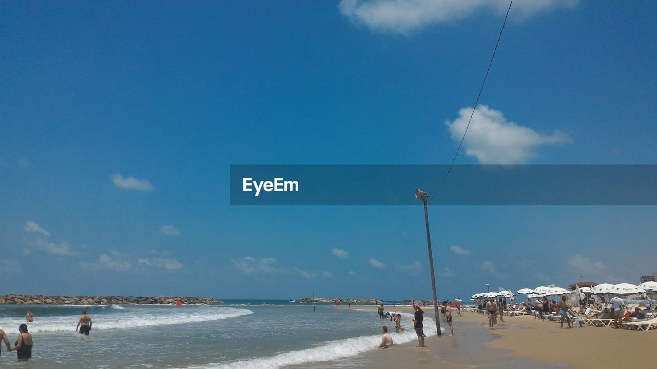 People at beach against sky