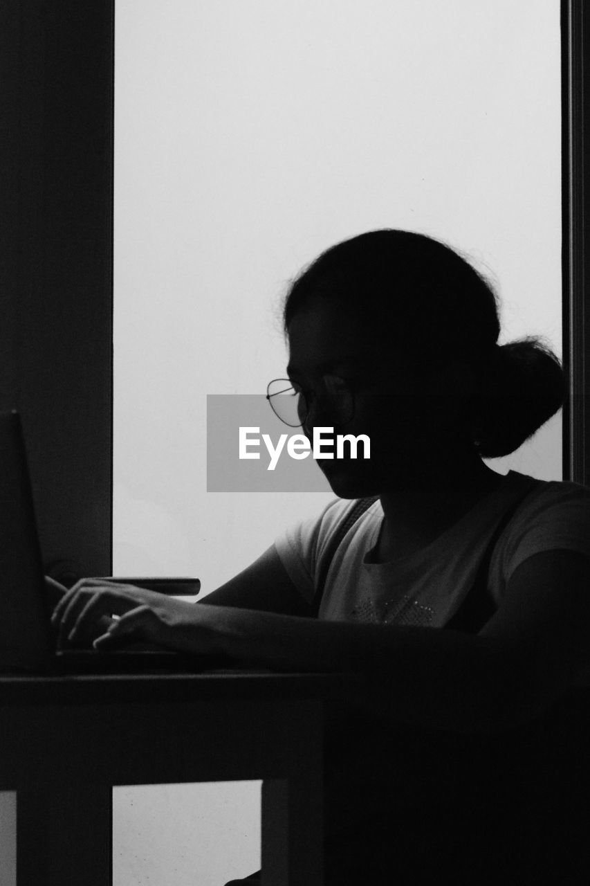 Young girl ia studying using a laptop while sitting on table at home