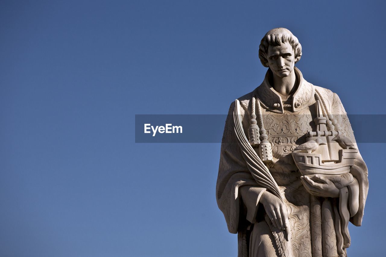 Low angle view of statue against blue sky