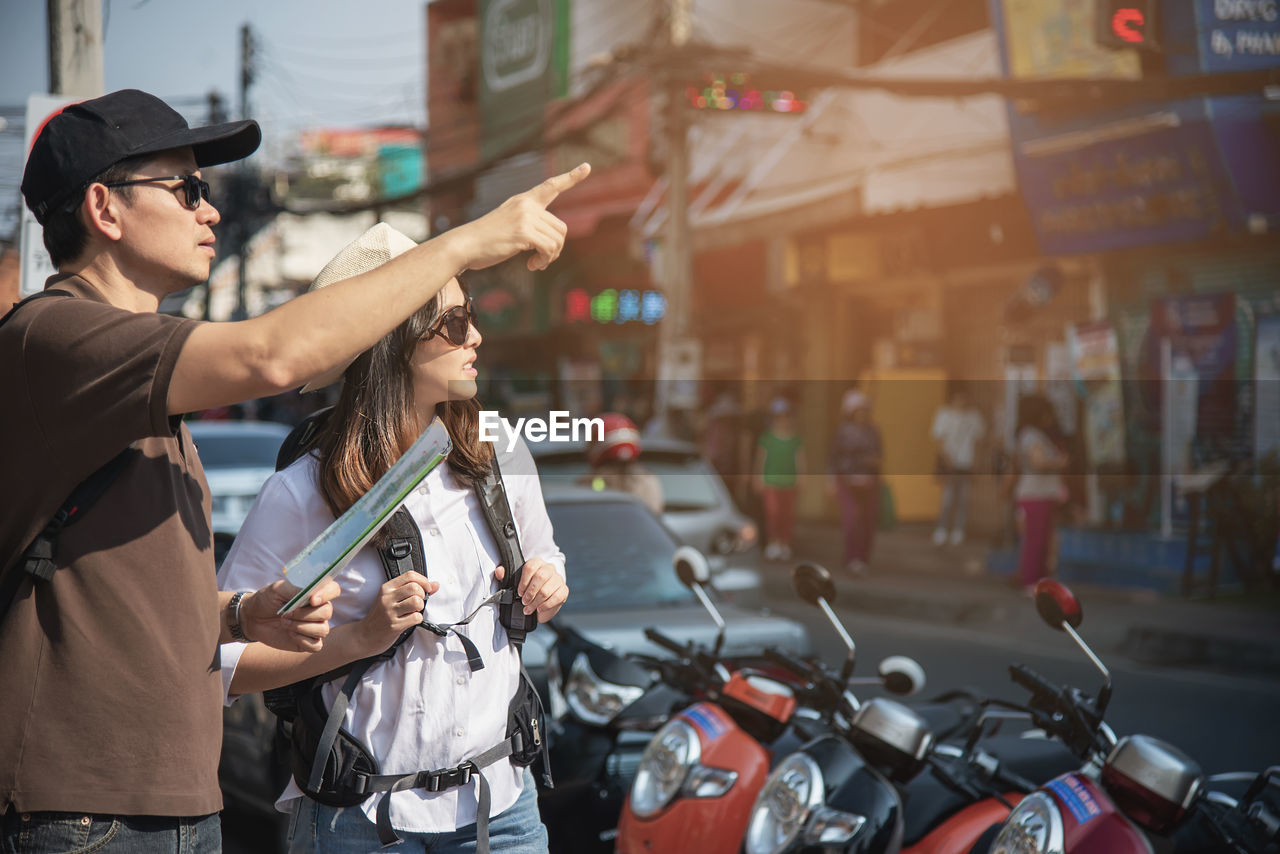 Man holding map pointing away while standing with women in city