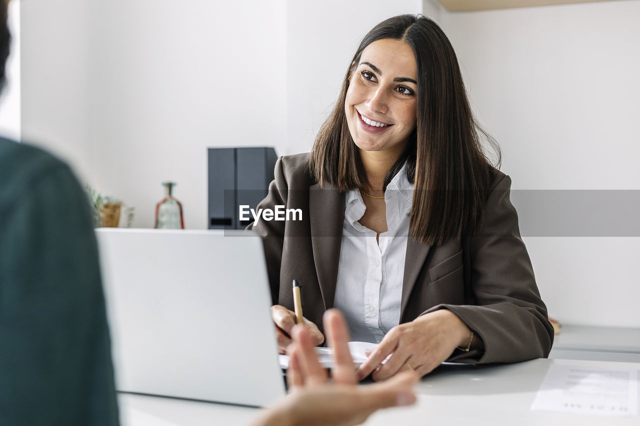 Smiling recruiter taking candidate's interview at desk