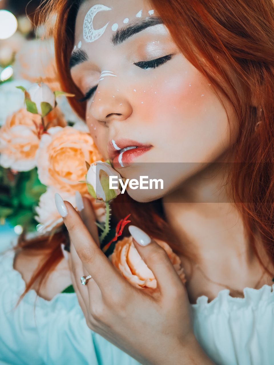 CLOSE-UP PORTRAIT OF A BEAUTIFUL WOMAN WITH RED FLOWER