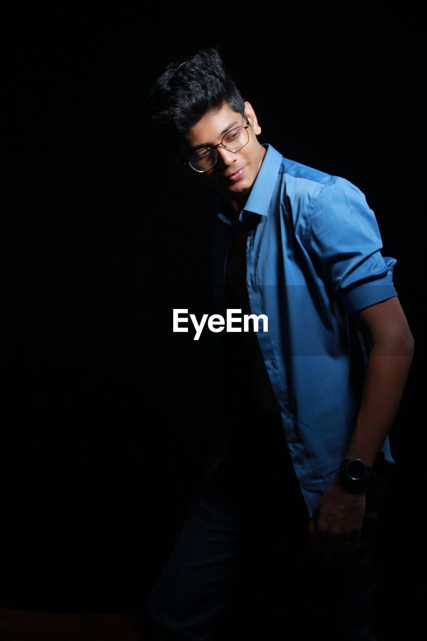 Young man standing against black background