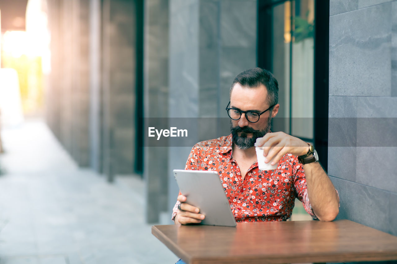 Man using digital tablet while sitting at table