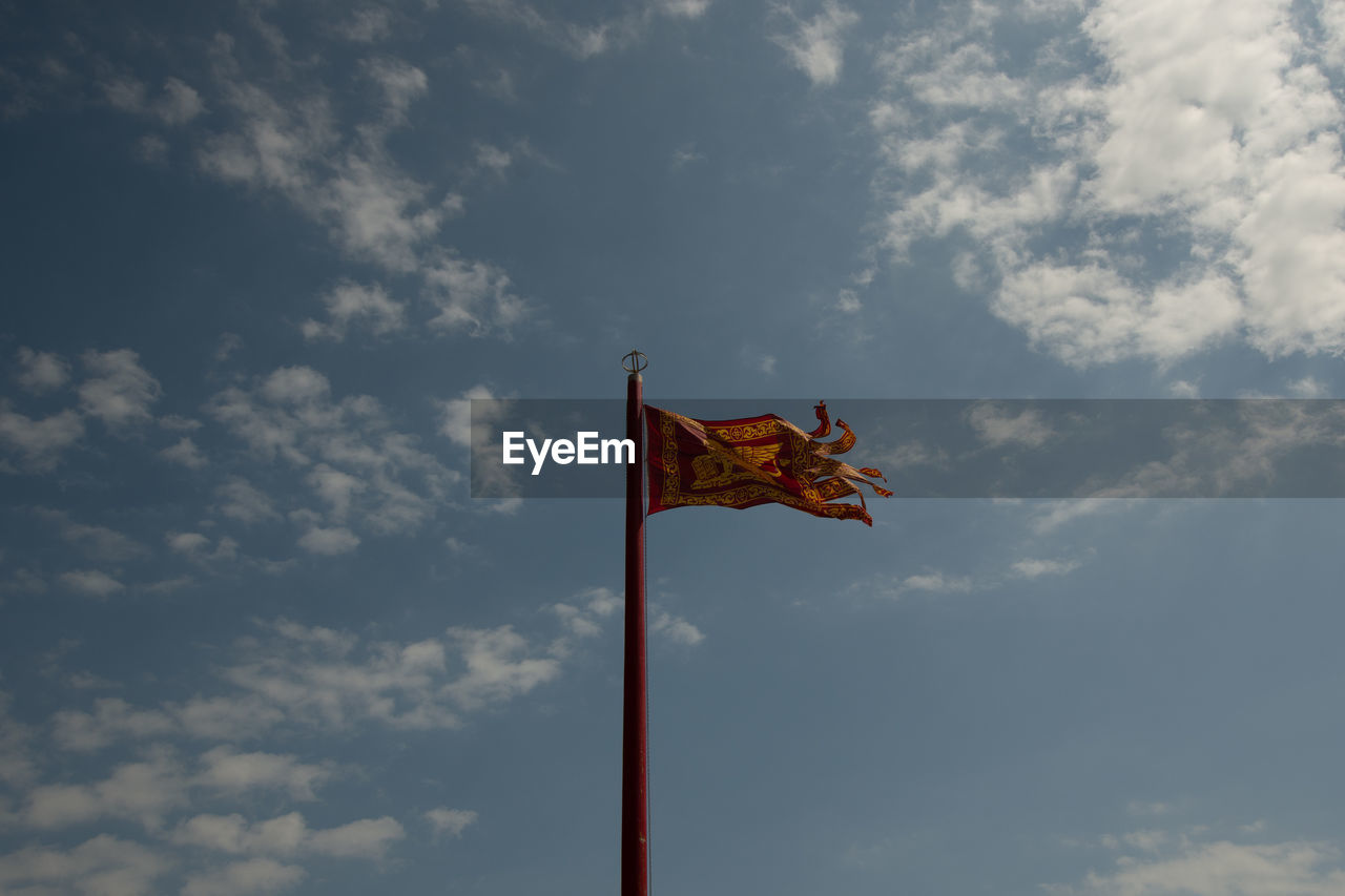 Low angle view of flag waving against cloudy sky