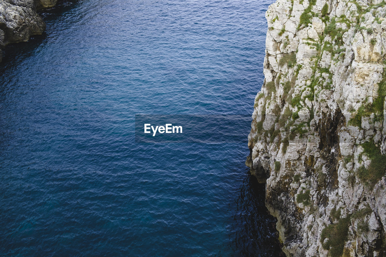 High angle view of rocky cliff by sea