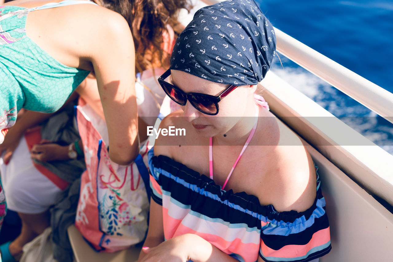 High angle view of young woman wearing sunglasses sitting in boat