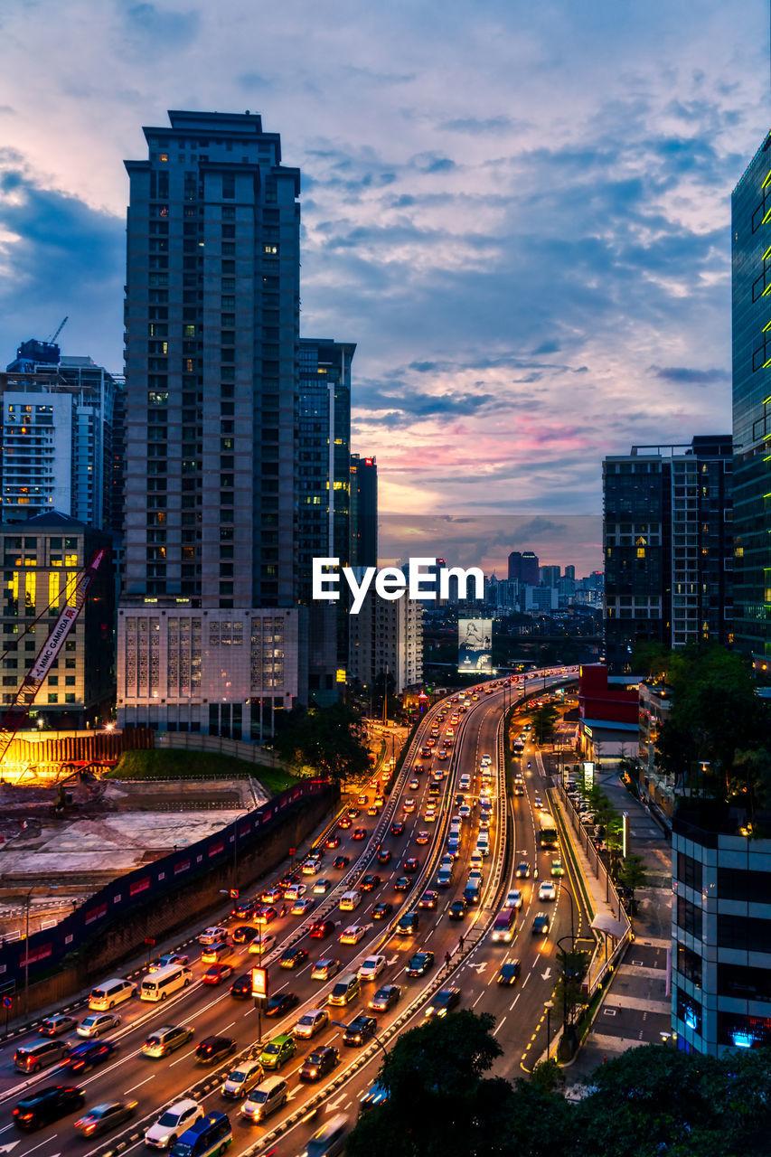 High angle view of illuminated city street and buildings against sky