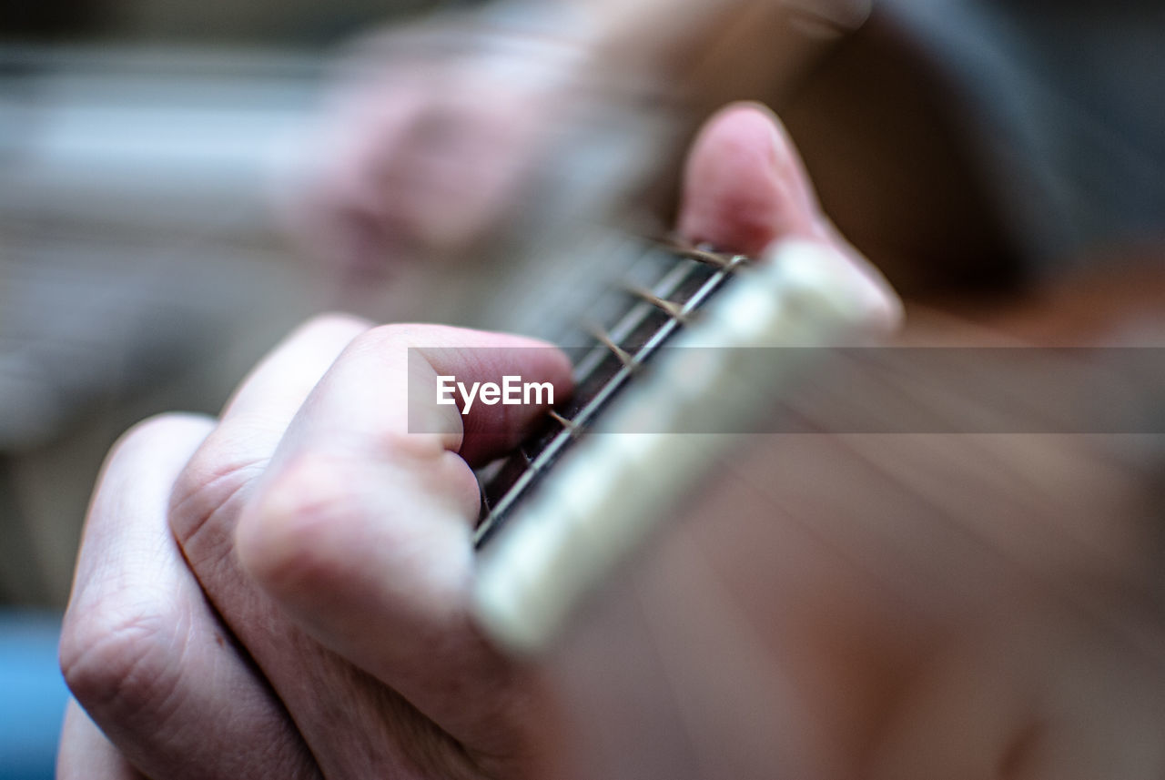 Close-up of hands of a man playing guitar