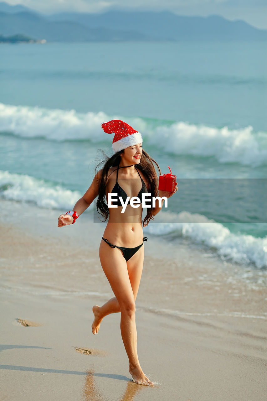 Happy young woman wearing bikini running at beach