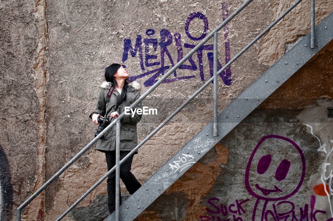 Young woman looking at graffiti on wall while moving downstairs