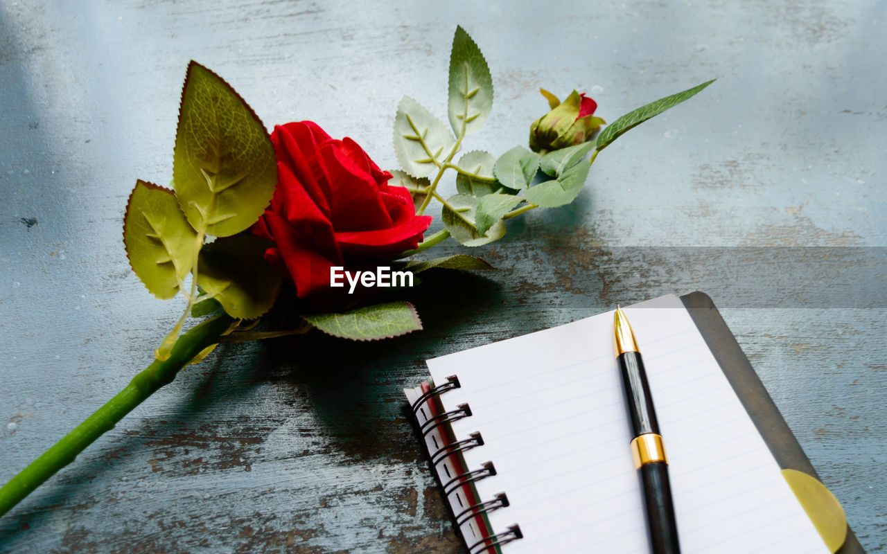 CLOSE-UP OF RED ROSE ON TABLE