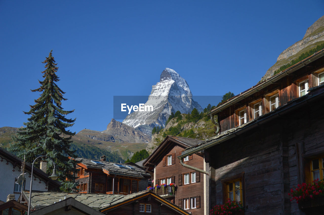 Houses by snowcapped mountains against clear sky