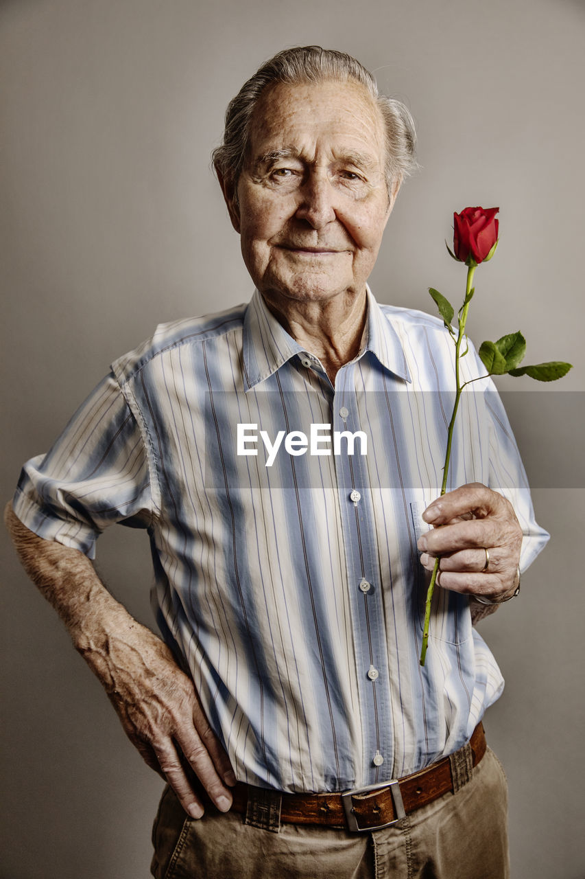 Portrait of smiling senior man with red rose