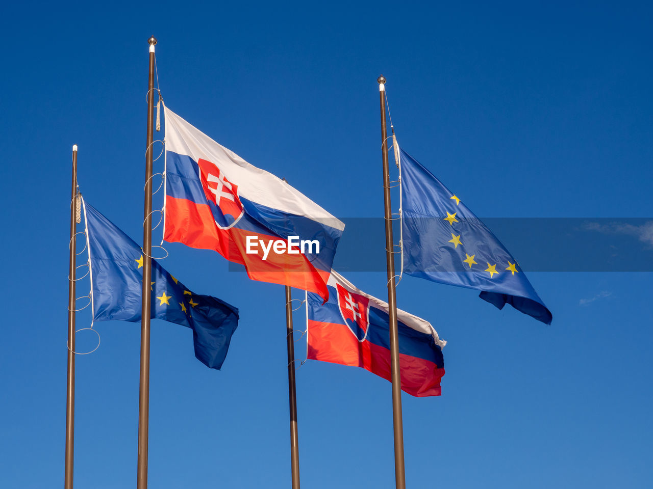 Low angle view of flags against clear blue sky