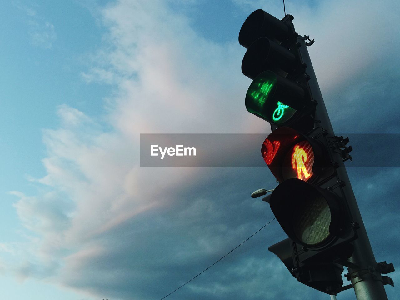 Low angle view of road signal against cloudy sky at dusk