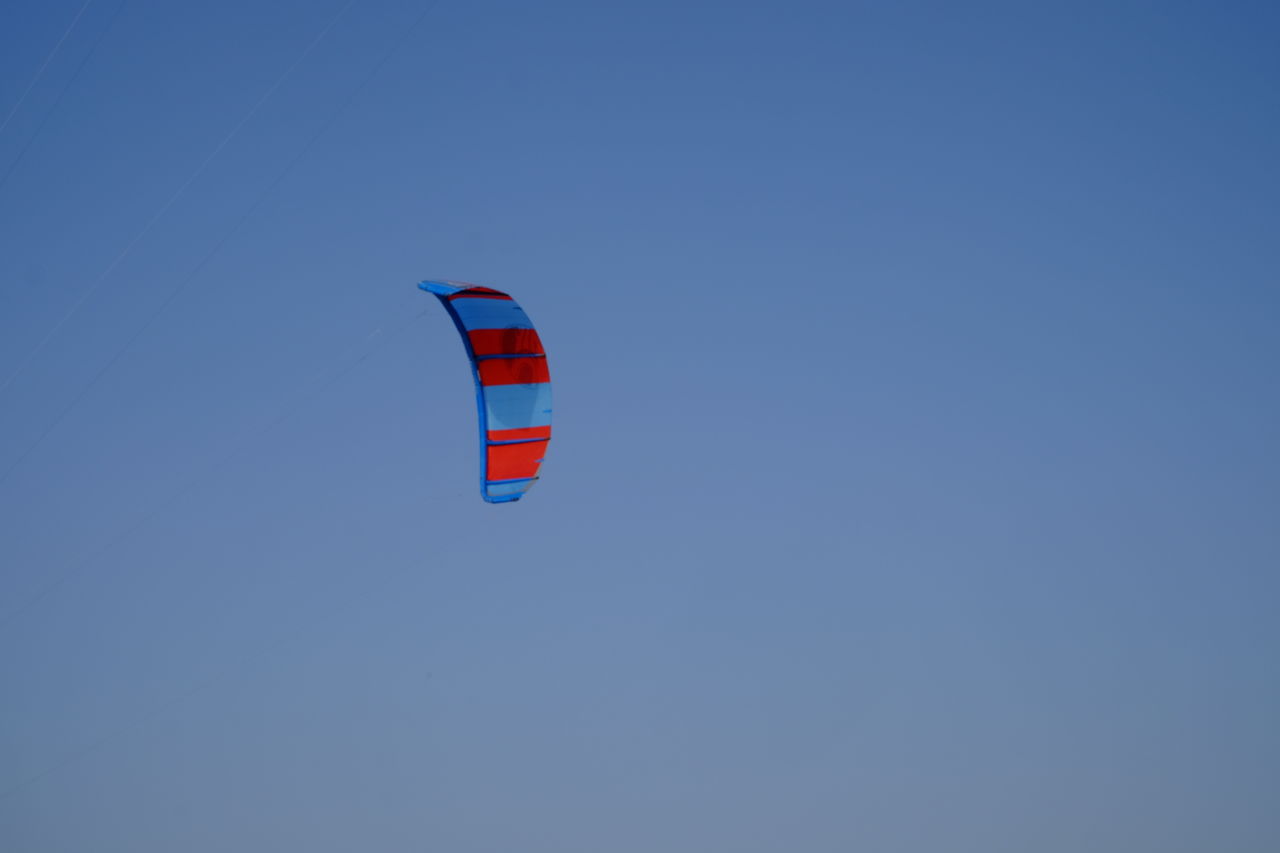 LOW ANGLE VIEW OF PERSON FLYING AGAINST CLEAR BLUE SKY