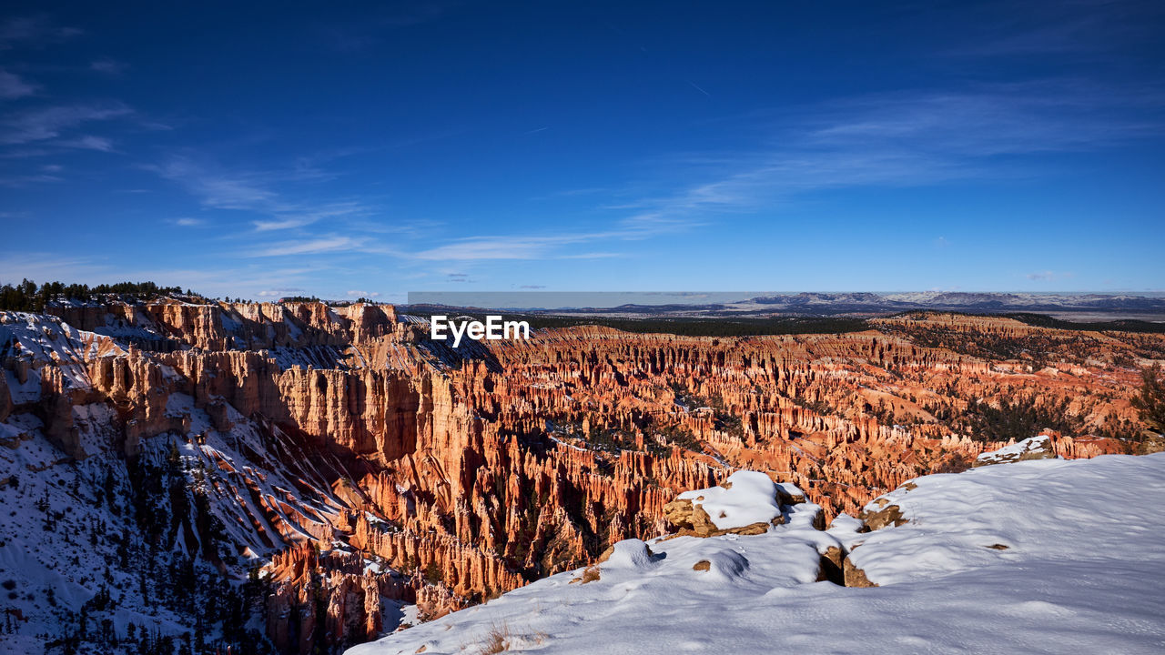 Scenic view of snowcapped mountains against blue sky