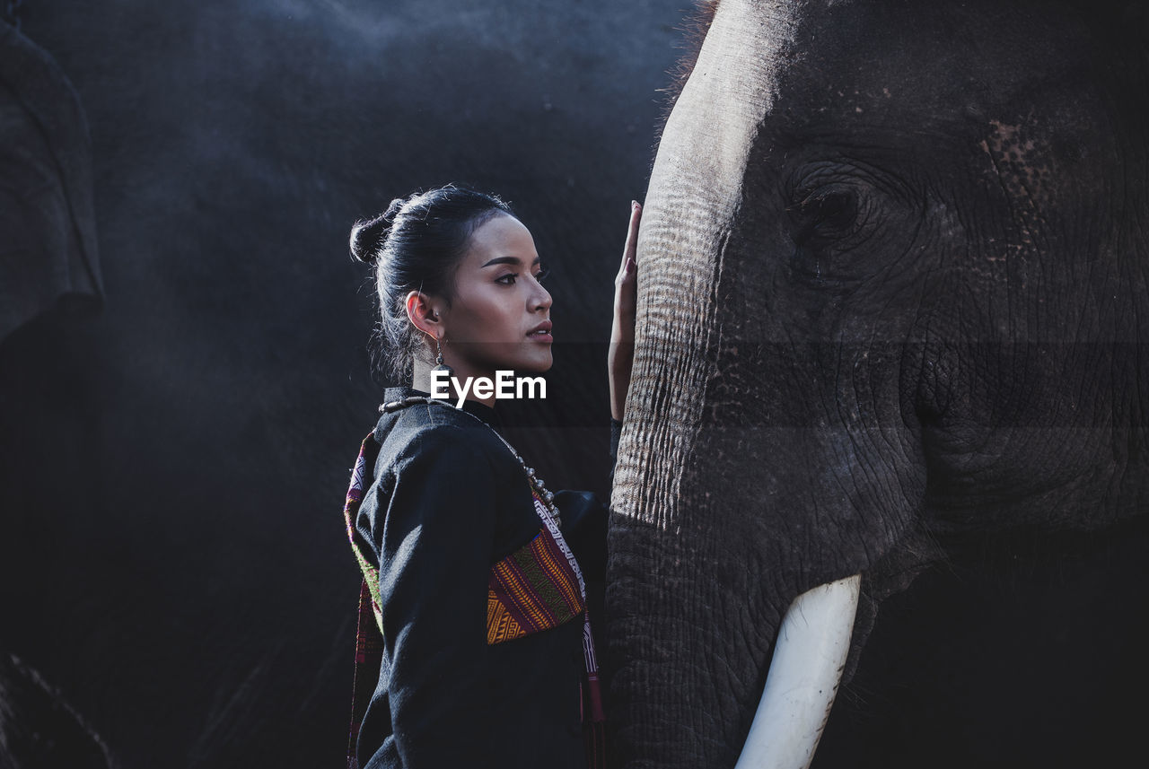 Smiling woman standing with elephant in forest