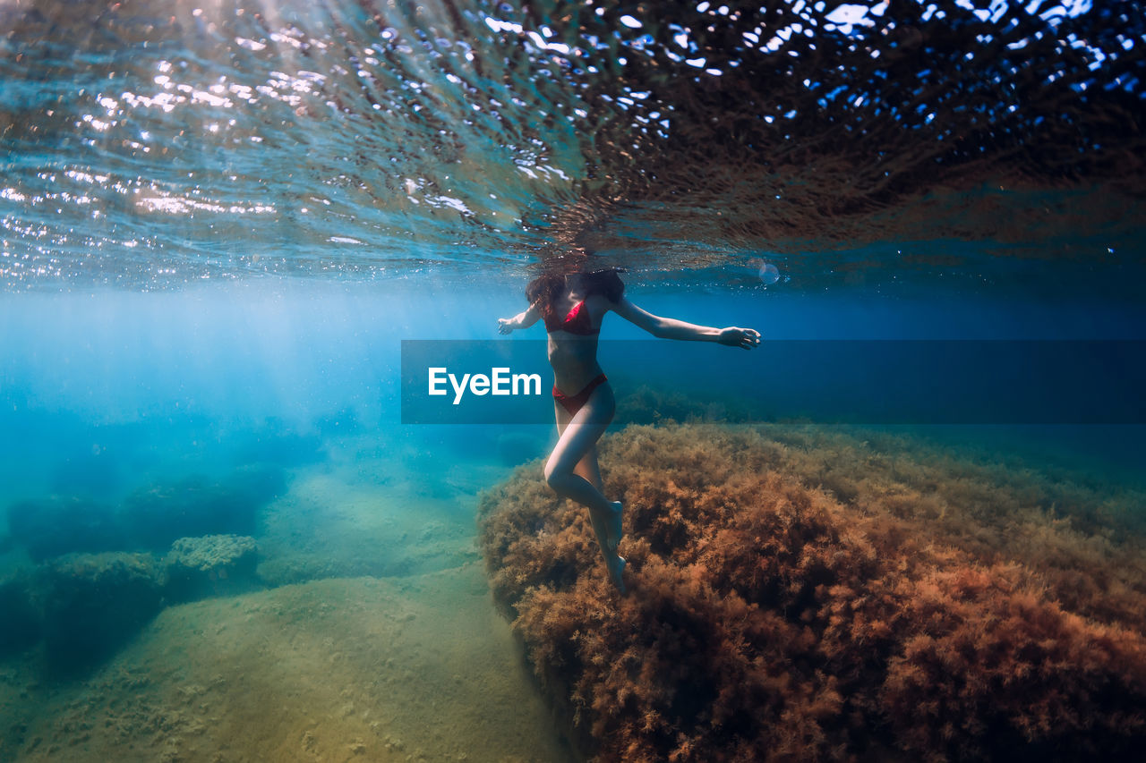 full length of young woman jumping in sea