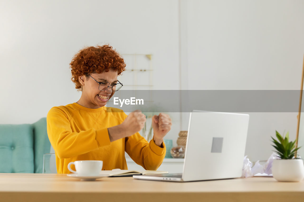 side view of young woman using laptop while sitting on table