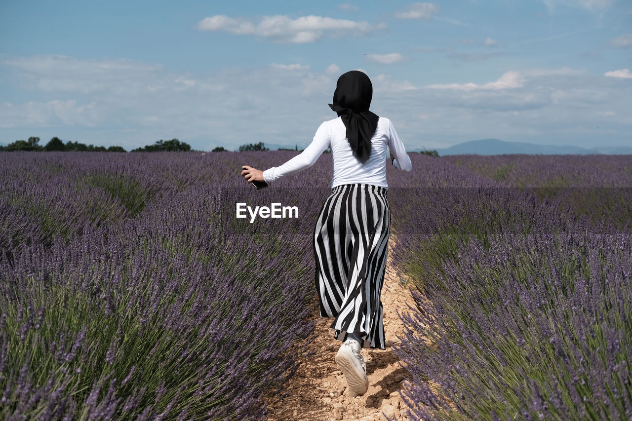 Cheerful woman running in lavender garden