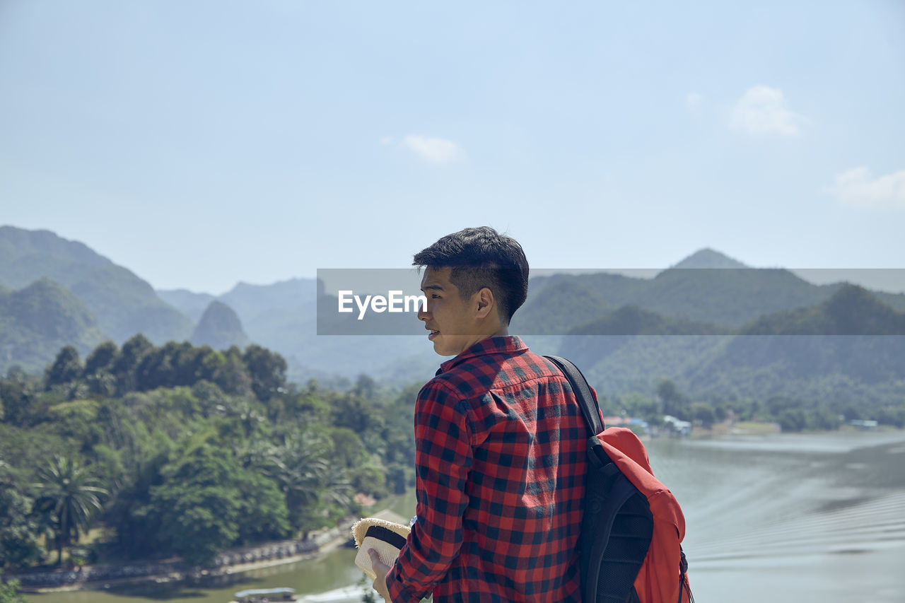 Rearview of male tourists standing look out over the mountains and rivers