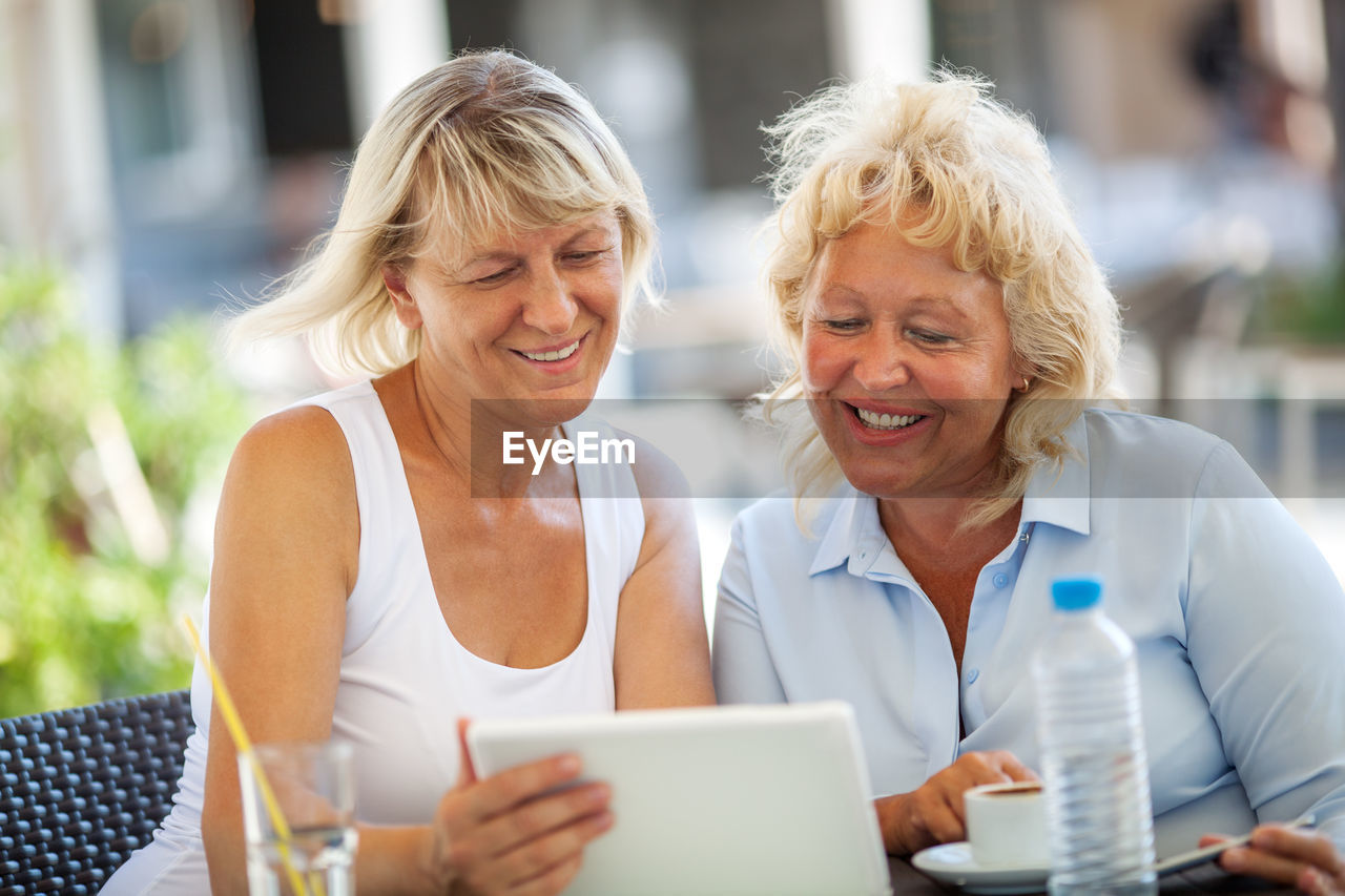 Happy senior female friends looking in digital tablet on table