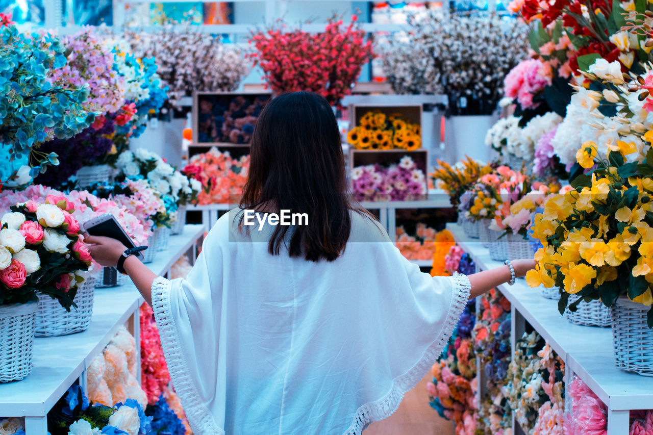 Rear view of woman amidst flowers in market