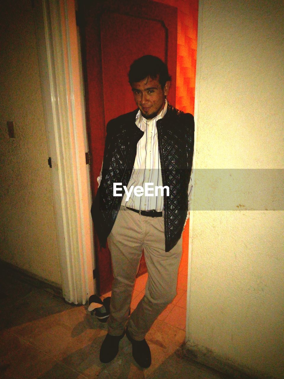 PORTRAIT OF YOUNG MAN STANDING AGAINST CURTAIN AT HOME