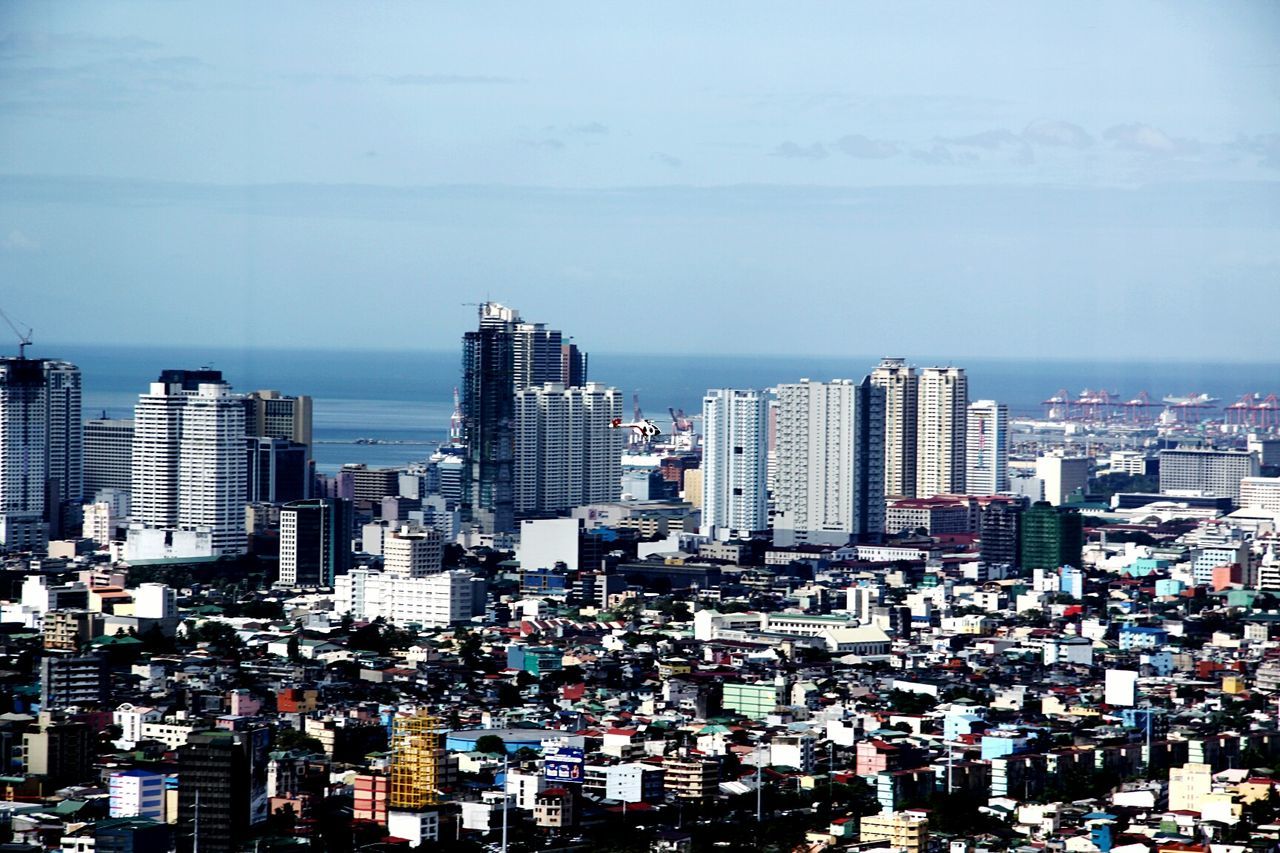 Cityscape by sea against sky