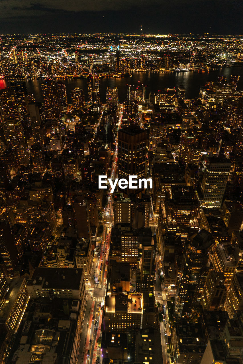 Aerial view of illuminated skyscraper buildings in city at night at high angle