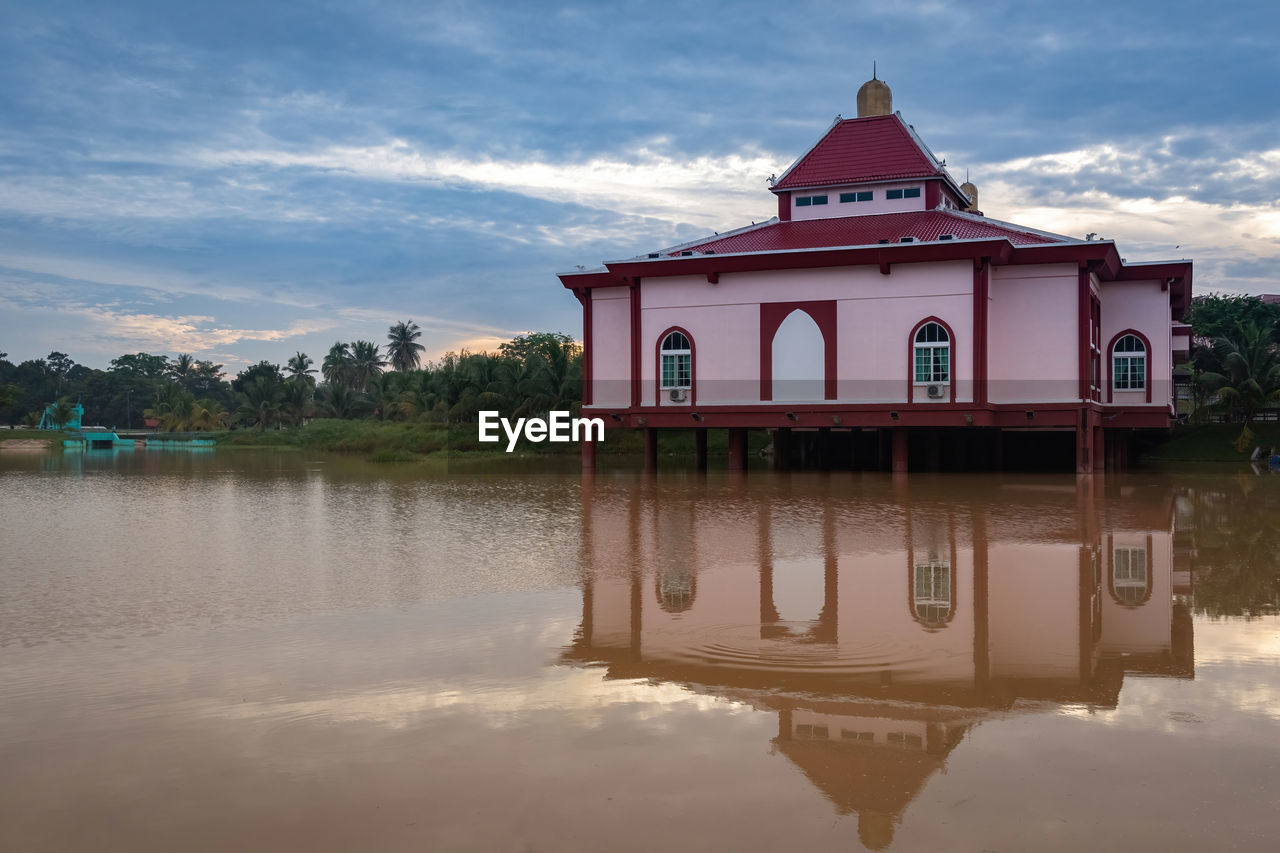 water, reflection, architecture, sky, cloud, built structure, building exterior, nature, building, lake, travel destinations, house, no people, landscape, environment, tranquility, travel, outdoors, religion, beauty in nature, scenics - nature, beach, tree, tourism, tower, red, land, plant, history, sunset