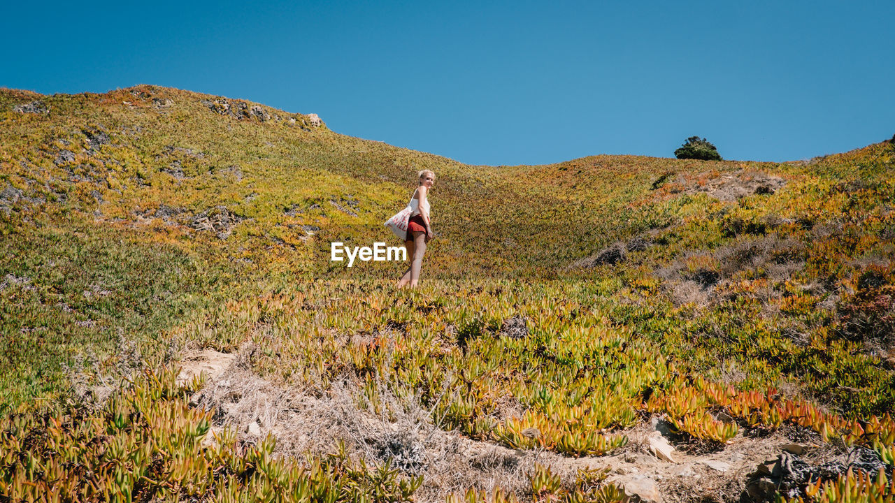 Low angle view of woman standing on mountain against clear sky