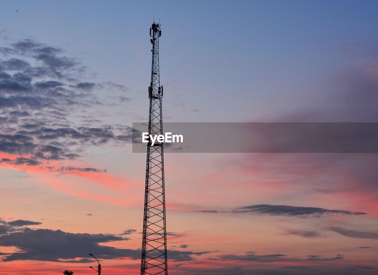 Low angle view of silhouette communications tower against sky during sunset