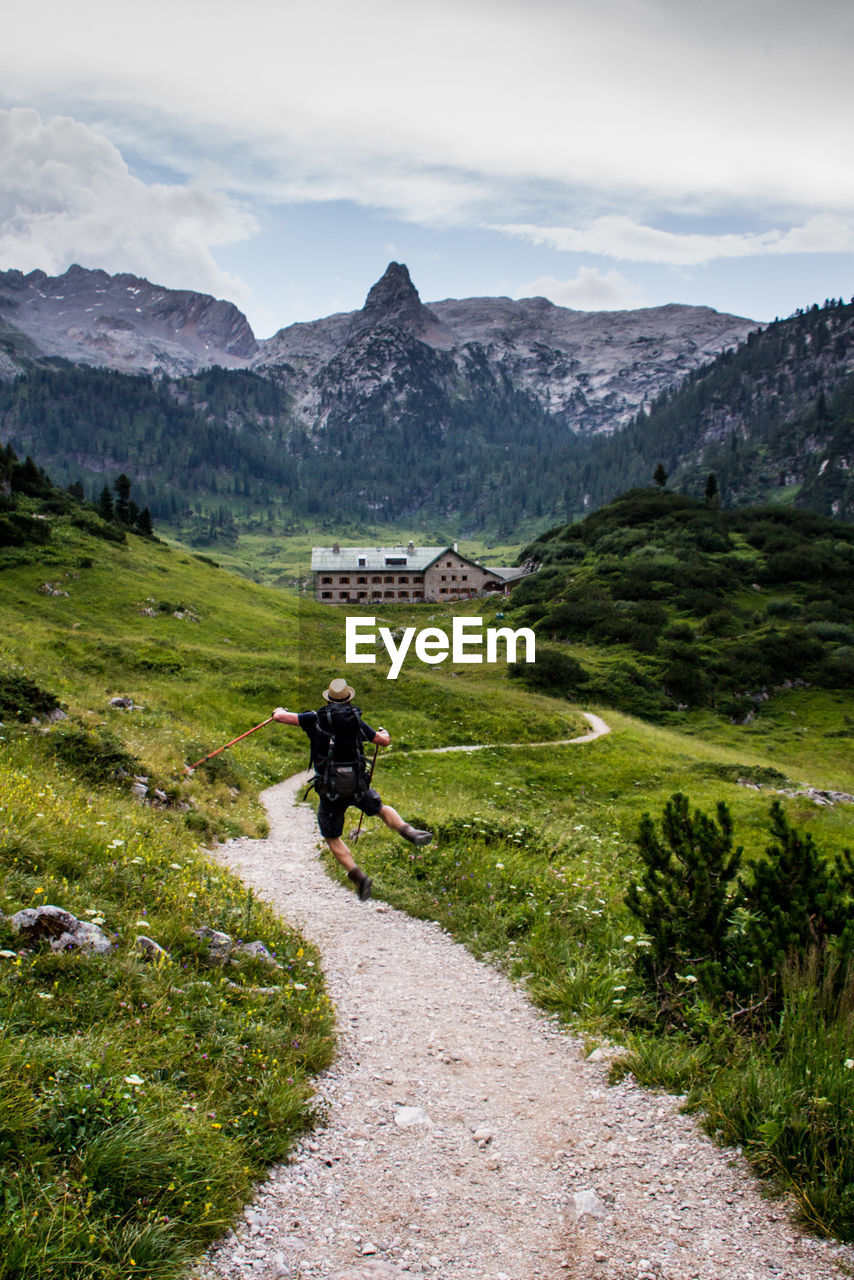 Rear view of man jumping while hiking on mountain