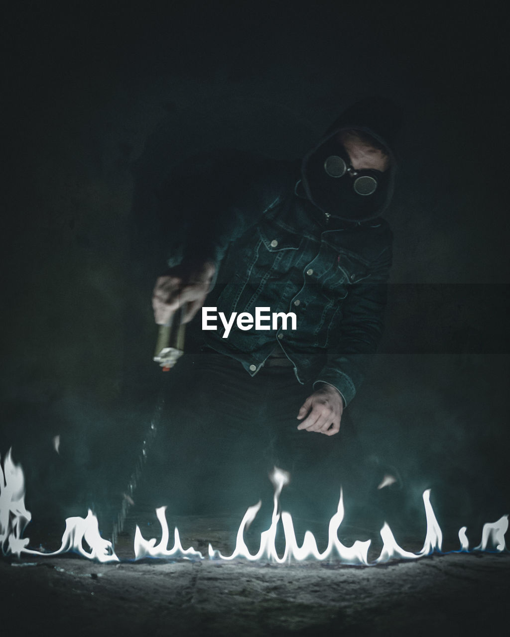 Man pouring oil on fire at night