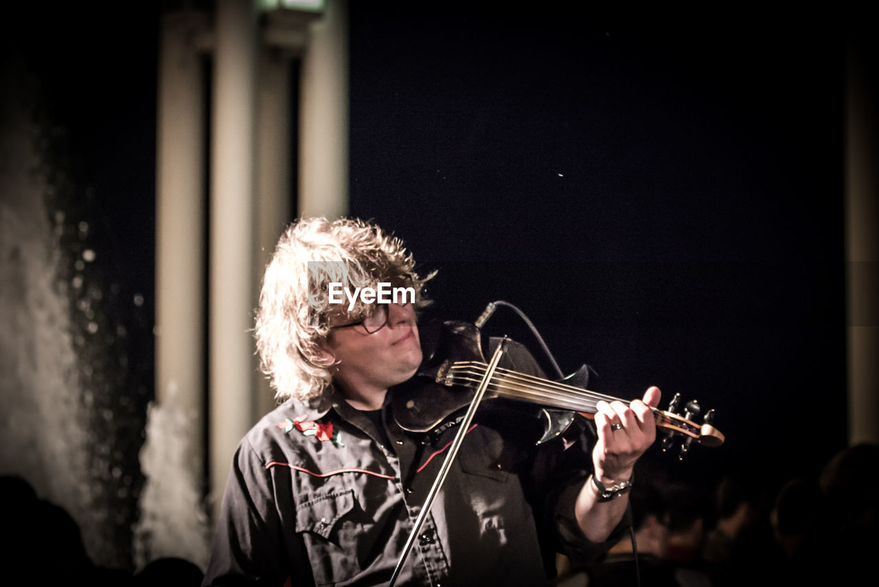 YOUNG WOMAN LOOKING AT MUSIC CONCERT