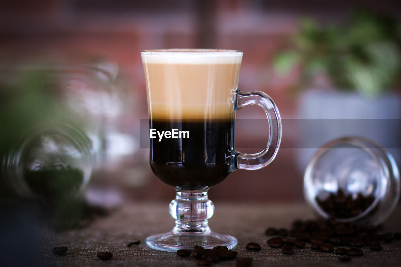 CLOSE-UP OF COFFEE CUP AND GLASS ON TABLE