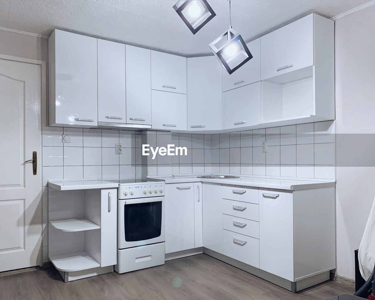 A modern, white, new kitchen with dark floor in a home