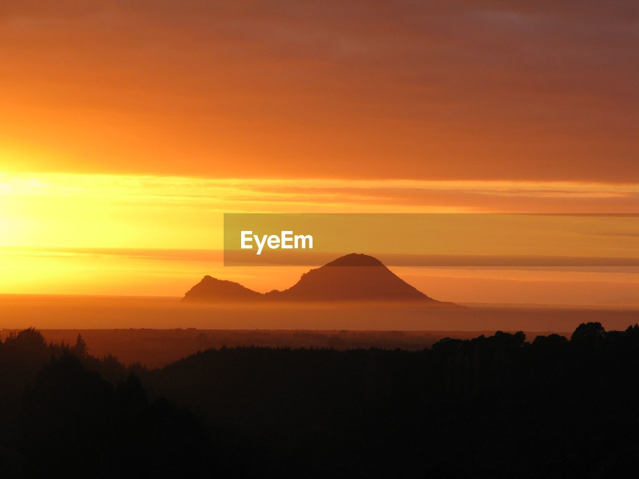 Scenic view of silhouette mountains against orange sky