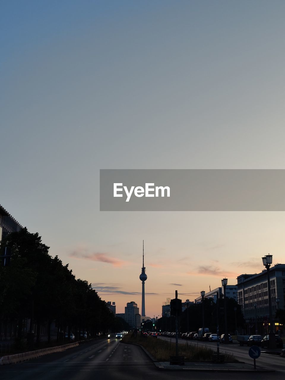 View of berlin tv tower and street against clear sky during sunset