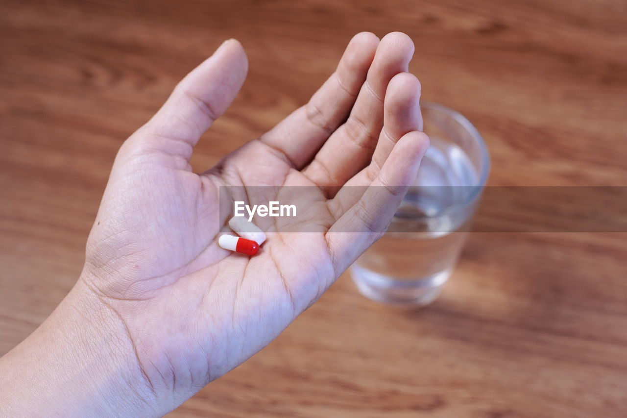 Cropped hand holding medicines over table