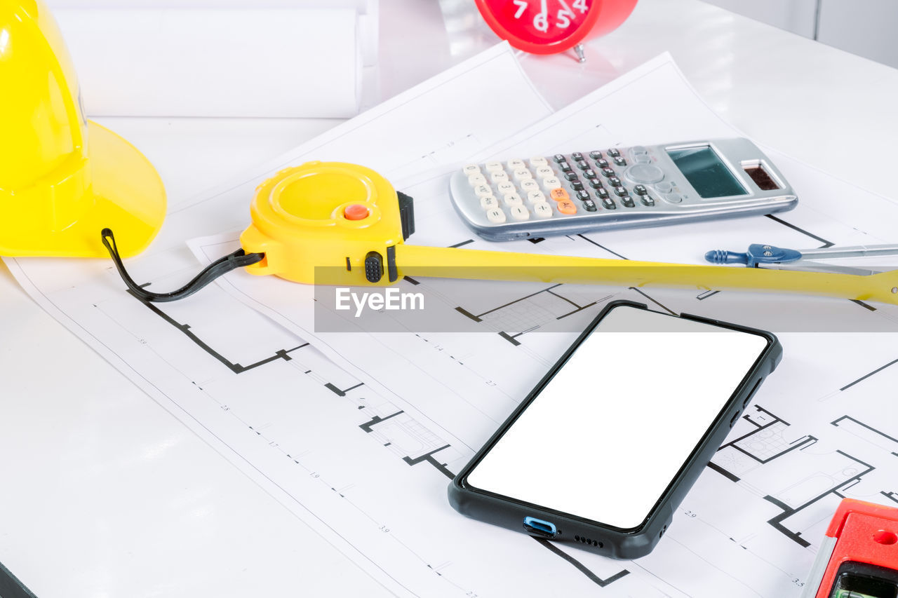 HIGH ANGLE VIEW OF MOBILE PHONE ON TABLE AND PAPER